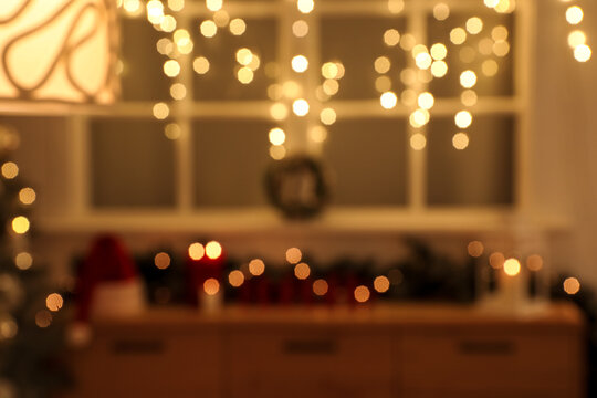 Blurred view of living room with commode and glowing Christmas lights at night - Powered by Adobe