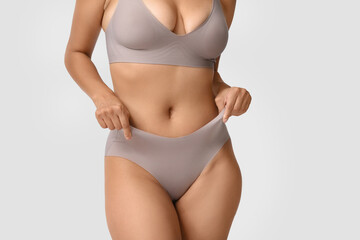 Beautiful young African-American body positive woman on grey background, closeup
