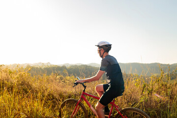 Obraz premium Cyclist riding a bike on a trail on a sunny day. He is wearing cycling gear and apparel. Inspirational image of a healthy lifestyle through cycling
