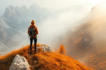 Obraz premium Young woman on mountain peak and beautiful mountain valley in haze at colorful sunset in autumn. Dolomites, Italy. Sporty girl, mountain ridges in fog, orange grass, golden sun in fall. Hiking, ai