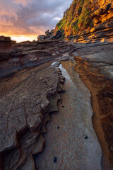 golden hour light on rocks during sunrise at little beach on nsw central coast of australia