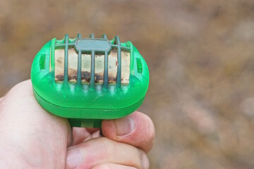 hand holding a one green old electric plastic fumigator in the street