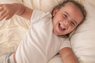 the little girl playing and tickling on the bed and having fun