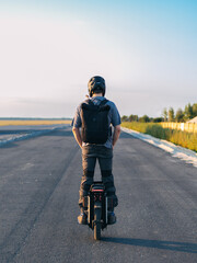 A man rides an electric wheel on the road , from the back view © pavelkant