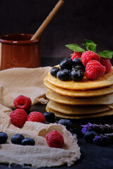 pancakes with berries and honey on dark background