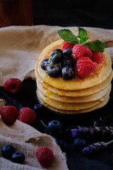pancakes with berries and honey on dark background