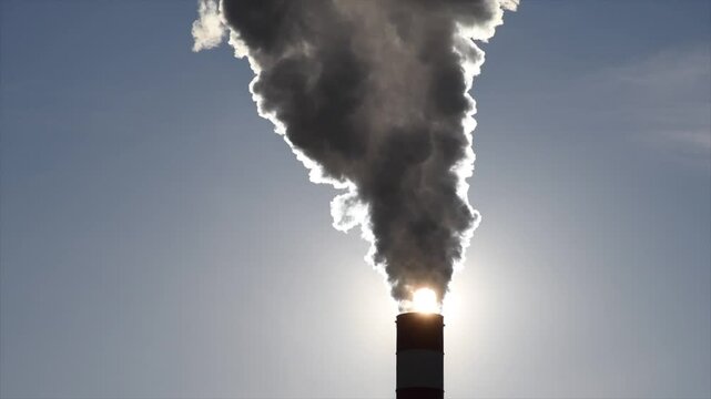 Industrial factory chimney releasing thick smoke into the atmosphere at sunset. Ideal for projects focused on pollution, environmental issues, climate change, and industrialization.