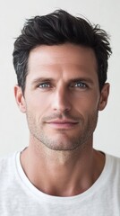 Fototapeta premium Handsome male model with short dark hair and blue eyes posing in front of white background