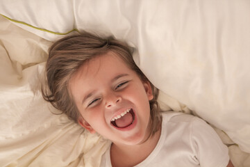 the little girl playing and tickling on the bed and having fun