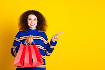 Photo of toothy beaming woman dressed striped sweater hold shopping bags indicating empty space...