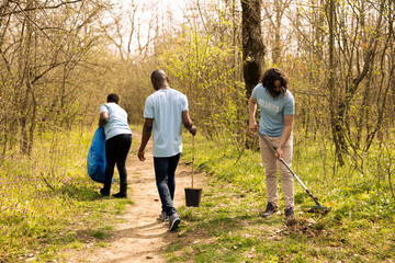 Male environmentalist raking dry leaves to help forest ecosystem restructuration, working in unity to protect the natural habitat. Volunteer takes action for a conservation project.