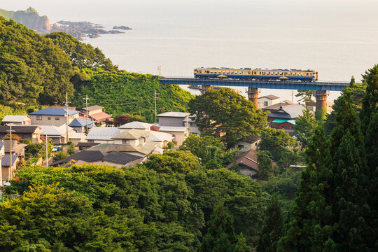 雄大な日本海が広がる詩情あふれる夕景を背景に五能線の気動車が走る