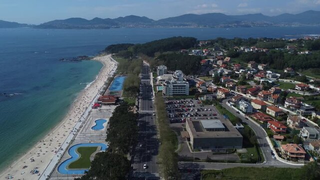 Aerial view of Playa de Samil, the main beach of Vigo in Galicia in northwest Spain. Sunny day, crystal clear blue sea. Houses, streets. Drone take.