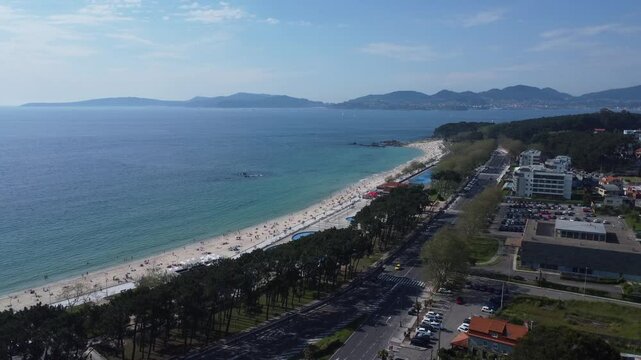 Aerial view of Playa de Samil, the main beach of Vigo in Galicia in northwest Spain. Sunny day, crystal clear blue sea. Houses, streets. Drone take.