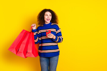 Photo of pleasant girl with perming coiffure holding smartphone shopping bags look empty space...
