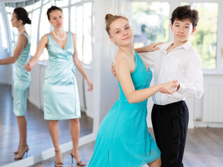 Passionate young ballroom enthusiasts, teenage girl and boy practicing graceful waltz routine in...