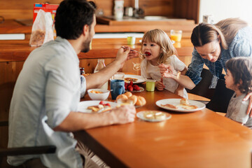 Happy family enjoying breakfast together in cozy kitchen