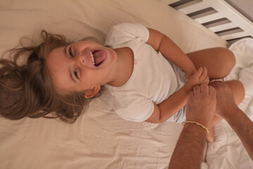 the little girl playing and tickling on the bed and having fun