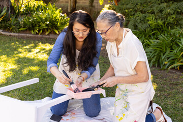 Obraz premium Painting and assembling furniture, asian granddaughter and grandmother bonding in diy project