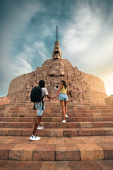 Pareja latina viajera, tomada de la mano, subiendo las escaleras del monumento a la patria en...