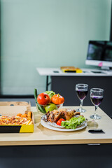 A business office is set for a Halloween party, with food spread across a desk pizza, bread, chicken grill, French fries, salad, and beer ready for celebration, but no people present.
