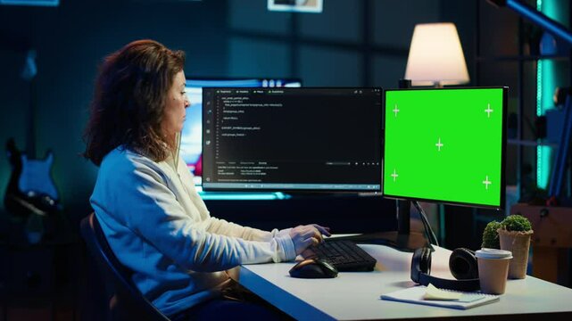 Developer doing software debugging on green screen PC at home, checking lines of code displayed on monitors. IT professional in living room fixing coding problems on mockup computer, camera A