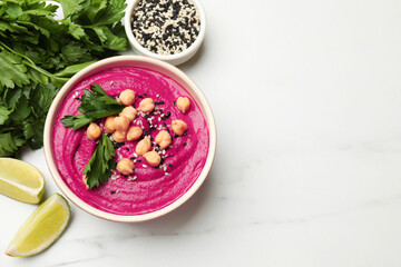 Tasty beetroot hummus in bowl and products on white marble table, flat lay. Space for text