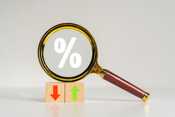 Magnifying glass and wooden blocks with percentage sign, up and down icon. Interest rate