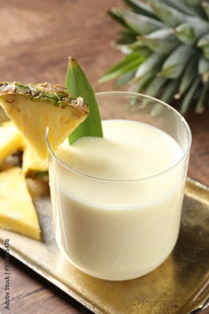 Wall mural Tasty pineapple smoothie in glass and fresh fruit on wooden table, closeup