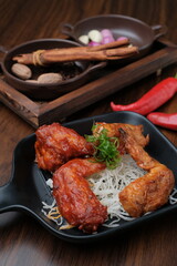 Fried chicken wings. Chicken wings on a wood background. Barbecue meat, grill. Sauce in bowls, ketchup, mayonnaise, mustard, cheese sauce. Appetizing fried meat in the black plate