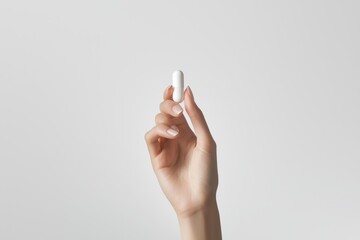 A hand holding a pill in a white pill bottle, The pill is white and he is a vitamin or supplement.