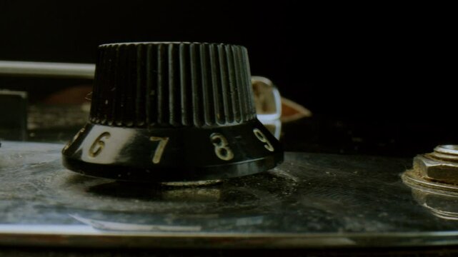 Volume and tone control knobs on metal pickguard of an electric guitar. Extreme close-up detailed shot