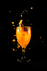Water splash from orange juice glass on black background