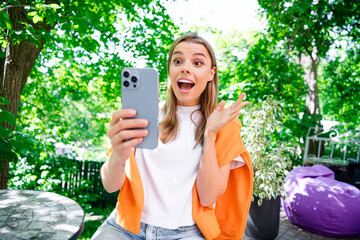 Photo of impressed cheerful lady wear casual t-shirt communicating modern device outdoors urban...
