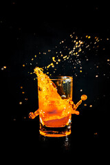 Water splash from orange juice glass on black background