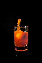 Water splash from orange juice glass on black background