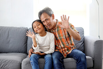 Cheerful Asian Family Father And Daughter Greeting With Waving Hands And Looking at Camera