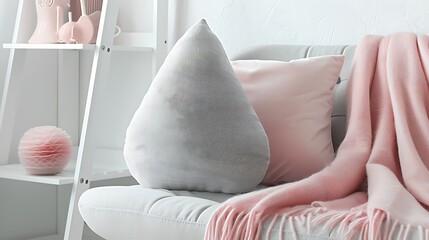 Grey pillow shaped like a teardrop on white shelf near to ladder and sofa with pink blanket