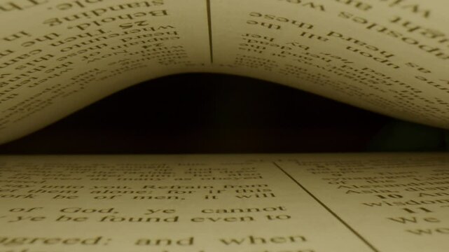 Paper pages with printed text in English against black background. Macro view, camera moving inside the book