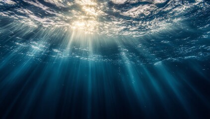 Underwater view of sunlight beams piercing through blue ocean water.