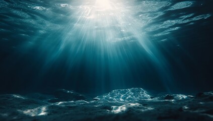 Sunlight beams through the deep blue ocean water, illuminating the sandy seafloor.