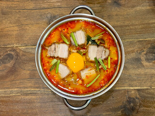 Tom yum, a famous national dish of Thailand, served inside a steel pan on a wooden table. Tom yum is a mixture of seafood, vegetables, poured with coconut milk. Hot and sour.