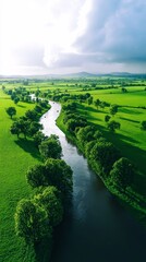 Fototapeta premium Aerial view of a serene river winding through lush greenery under a dramatic sky, showcasing the beauty of nature.
