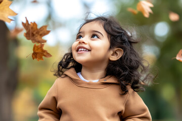 Arabian little girl smiling wearing sweatshirt playing at sunny autumn park