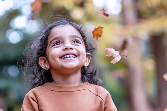 Indian little girl smiling wearing sweatshirt playing at sunny autumn park