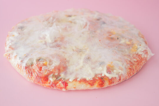 Delicious Frozen Pizza Featuring Cheese and Various Toppings, All Wrapped Securely in Plastic