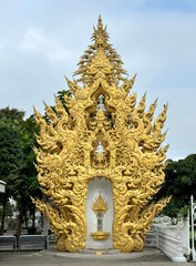 Golden Temple Chiang Rai, Thailand. This golden temple is located behind White temple, with its ornaments and engraving all covered in gold, surrounded by lake.
