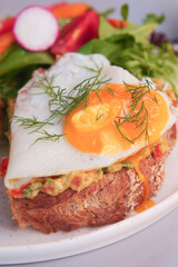 Savor delicious Avocado Toast with a Fried Egg, served with a Fresh Salad on the side