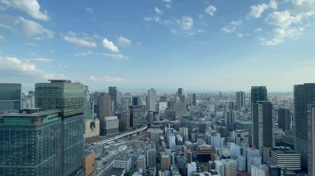 UMEDA, OSAKA, JAPAN - JUNE 2024 : Aerial high angle view around Osaka train station in daytime. View of crowded buildings at downtown area. Urban city and business concept video. Time lapse shot.