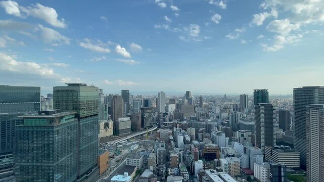 UMEDA, OSAKA, JAPAN - JUNE 2024 : Aerial high angle view around Osaka train station in daytime. View of crowded buildings at downtown area. Urban city and business concept video. Time lapse shot.